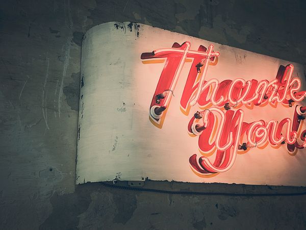A vintage neon sign that spells Thank you! in red neon
