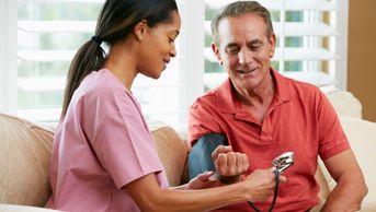 female caregiver taking blood pressure of male patient