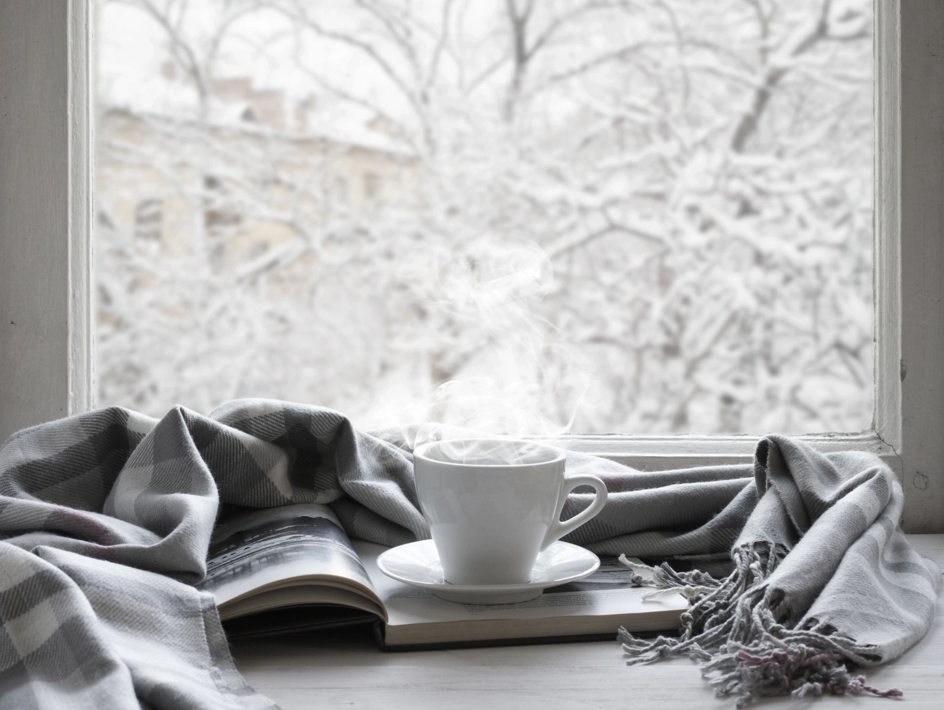 A cup of hot coffee on a book with a blanket laying around it