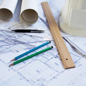 Image of pen, pencils, ruler resting on engineering blueprint.