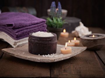 Coarse sugar in a jar, purple towels and tealight candles 