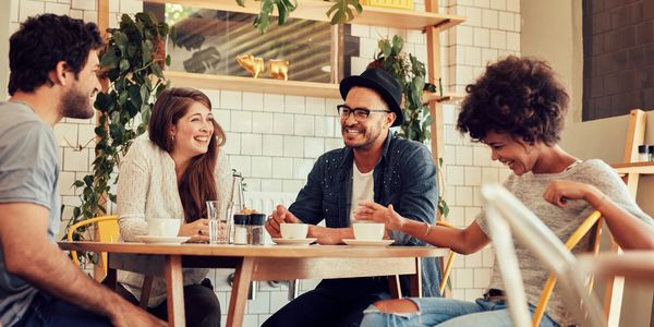 Group of adults meet and laugh at a coffee shop.