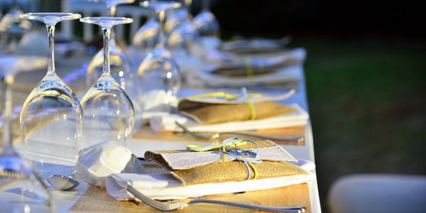 Table setting with gold placemats, napkins, silverware, and glassware.