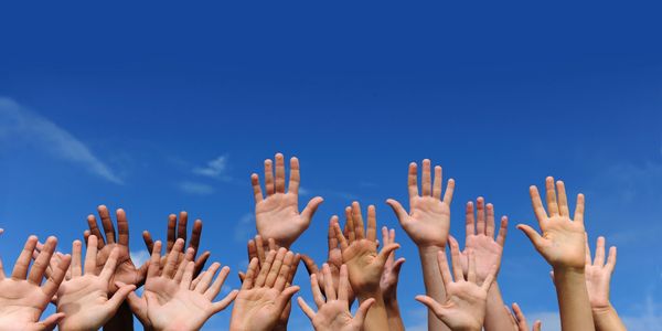 lots of hands up against a backdrop of a blue sky.