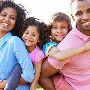 A Jubilant Family of Four, Bathed in Warm Sunlight, Radiating Joy and Security just got Insurance.