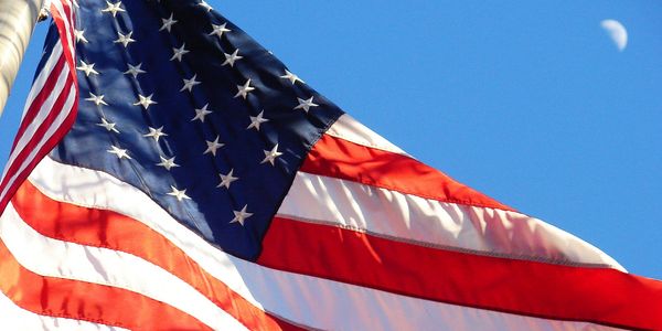 US flag waving beside a waxing moon
