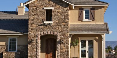 Front of a brown house with stone veneer and stucco.