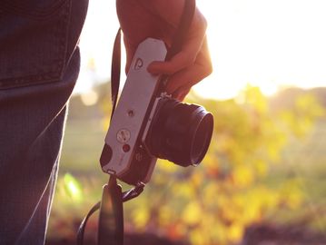 Person holding a camera in front of the sunset