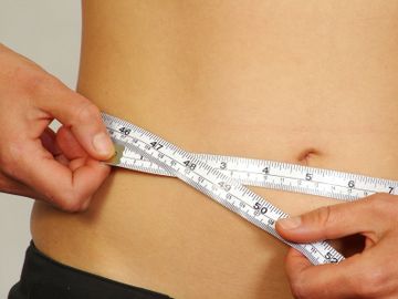 A toned stomach with a tap measure showing inch loss