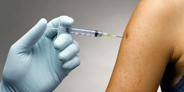 Hypodermic Needle injecting into arm held by gloved hand