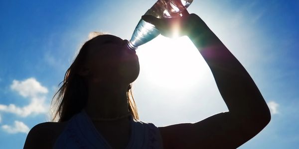 Silhouette of girl drinking bottle of water.
