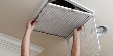 Technician replacing a dirty filter inside of a home