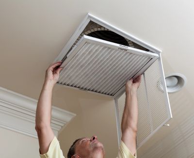 Man replacing duct filter in residential HVAC system.