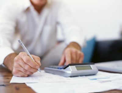 person sitting at a desk working with a calculator, paper and pen