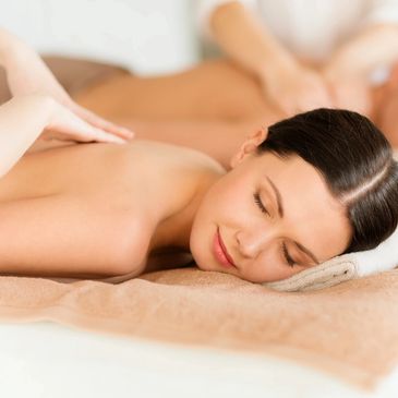 Couples Massage - women and man laying on two massage tables with smiles on their faces 