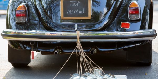 Photo of a wedding picture with the Just Married sign on the back of a car