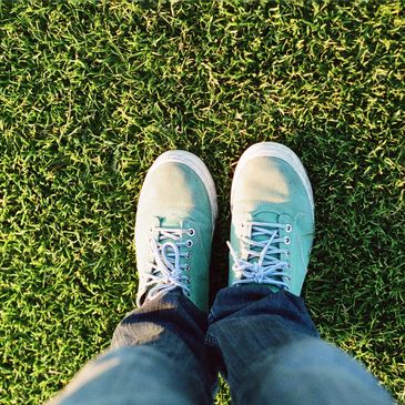 Two feet standing on green grass.