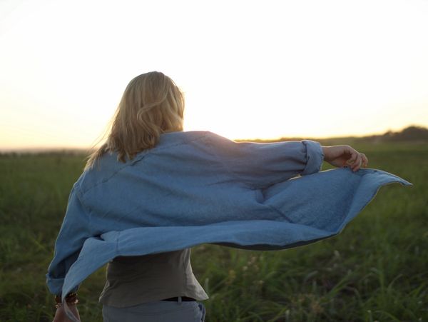 Woman in a blue shirt enjoying the breeze on a field