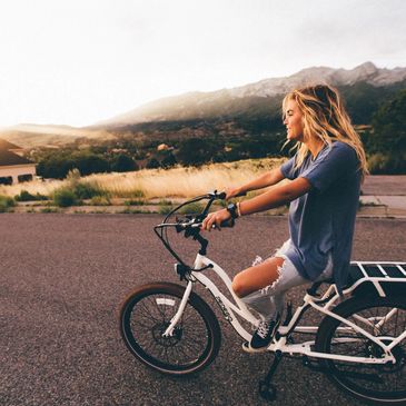 A young person with ripped jeans riding an ebike 