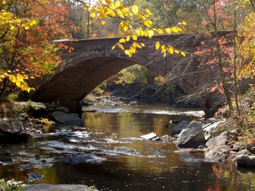 This is a stone bridge in New England with the fall leaves in all their color.