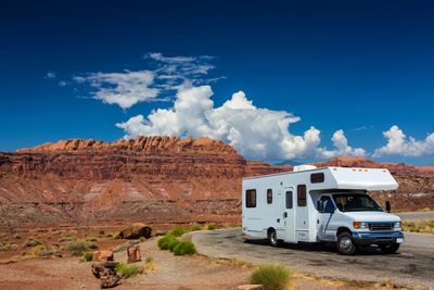 A large RV parked at a scenic turnout with red cliffs and vast desert on the horizon