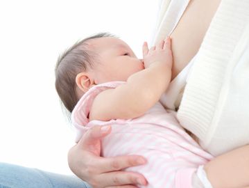 infant breastfeeding with her hand on the breast 