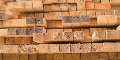 Multiple rows of evenly stacked wood timbers.