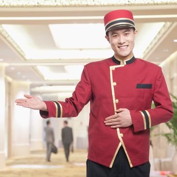 Hotel bellman with an open welcoming arm.