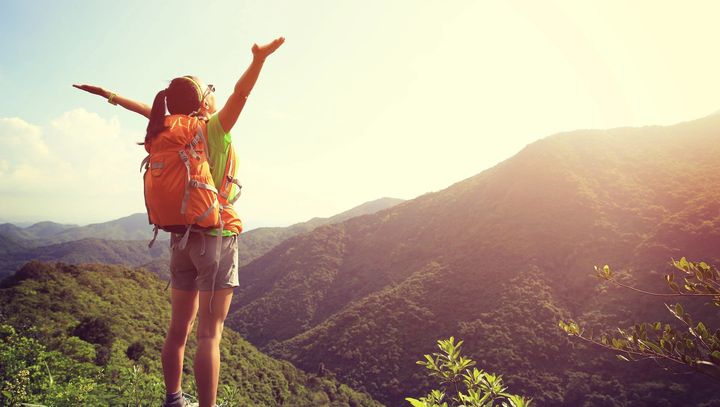 Woman hiker at top of mountain with outstretched arms celebrating