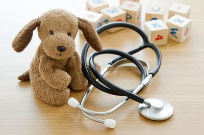 plush toy dog sitting next to stethoscope and children's blocks in pediatrician's office