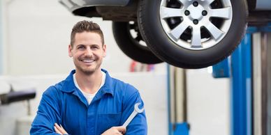 Mechanic with a wrench in front of a vehicle being repaired