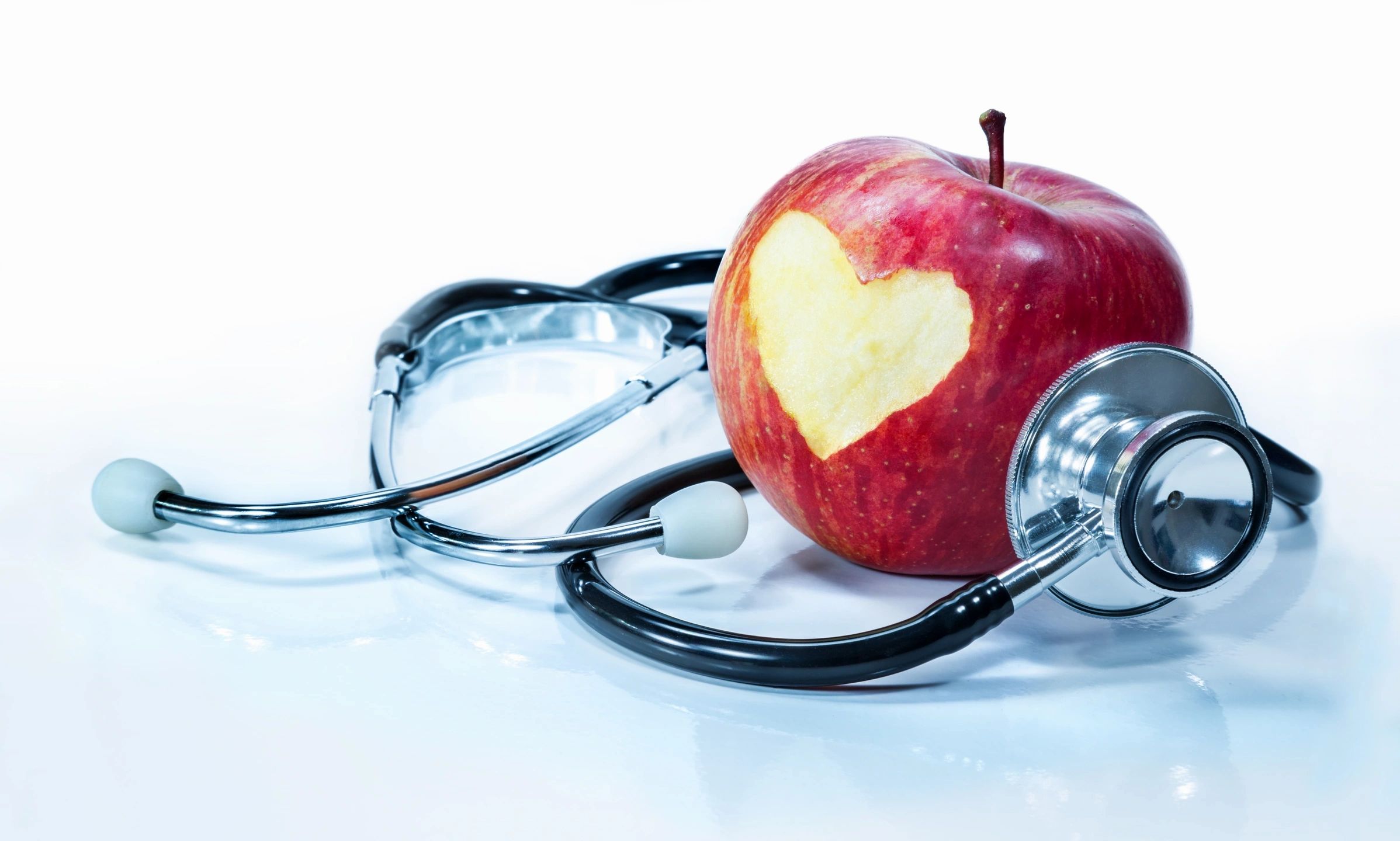 apple with a heart carved out and a stethoscope 