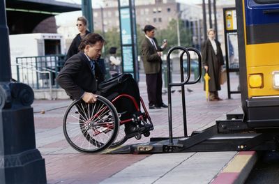 Man in a wheelchair getting onto a bus via an accessible ramp