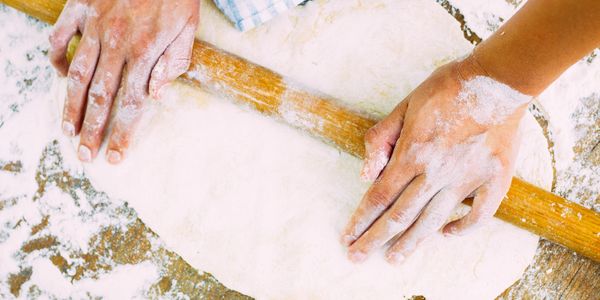 A person rolling a cake dough with his hands