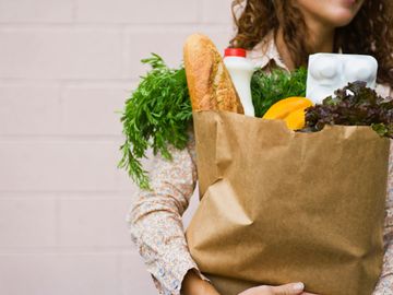 Woman carrying grocery bag filled with food