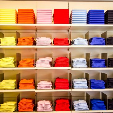 Stacks of tops displayed on shelving in a variety of colours.