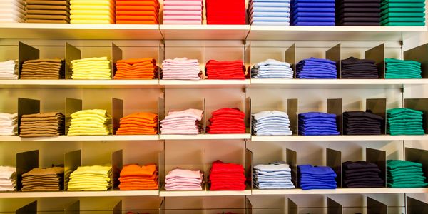 T-shirts on big shelf with a broad range of colours, from Brown To Green.