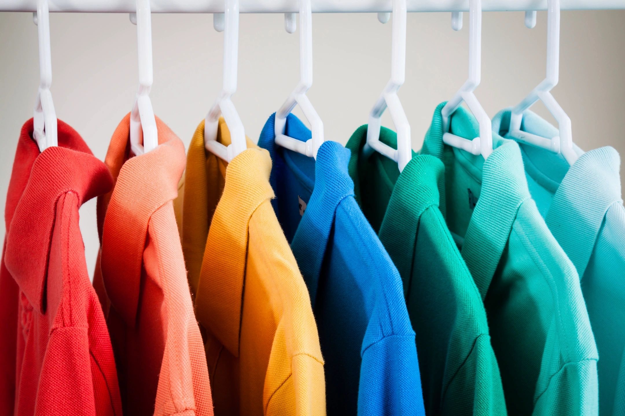 rainbow of shirts, hangers with multiple dry cleaned shirts, white hangers,