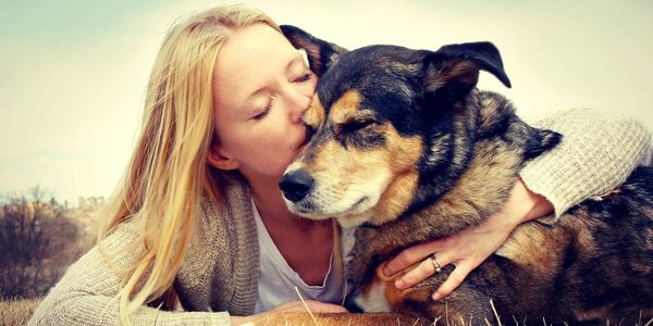 Woman kissing mixed breed dog