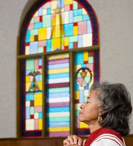 Image of a woman praying in church.