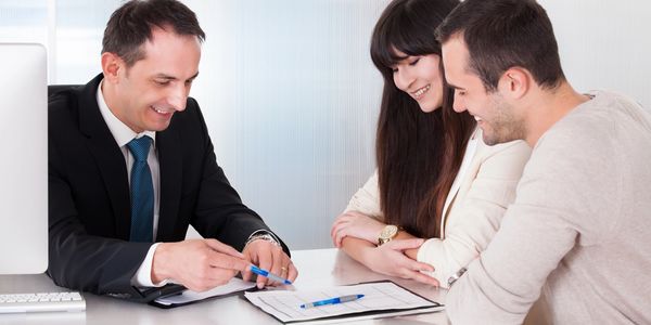 Businessman showcasing a pricing sheet to couple.