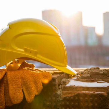 picture of hard hat resting on ground with pair of gloves next to it. 