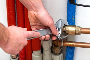 plumber with a wrench tightening a pipe