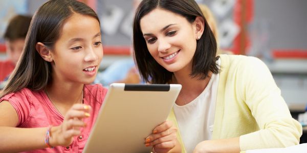 A teacher with a young student using a tablet