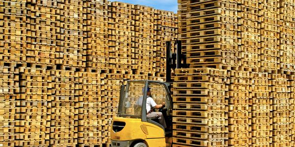 wooden pallet stacked with a forklift about to move a pile of pallets