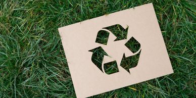 A recycling symbol cut out on a tile placed on grass