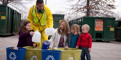 A man teaching a bunch of kids about recycled plastic