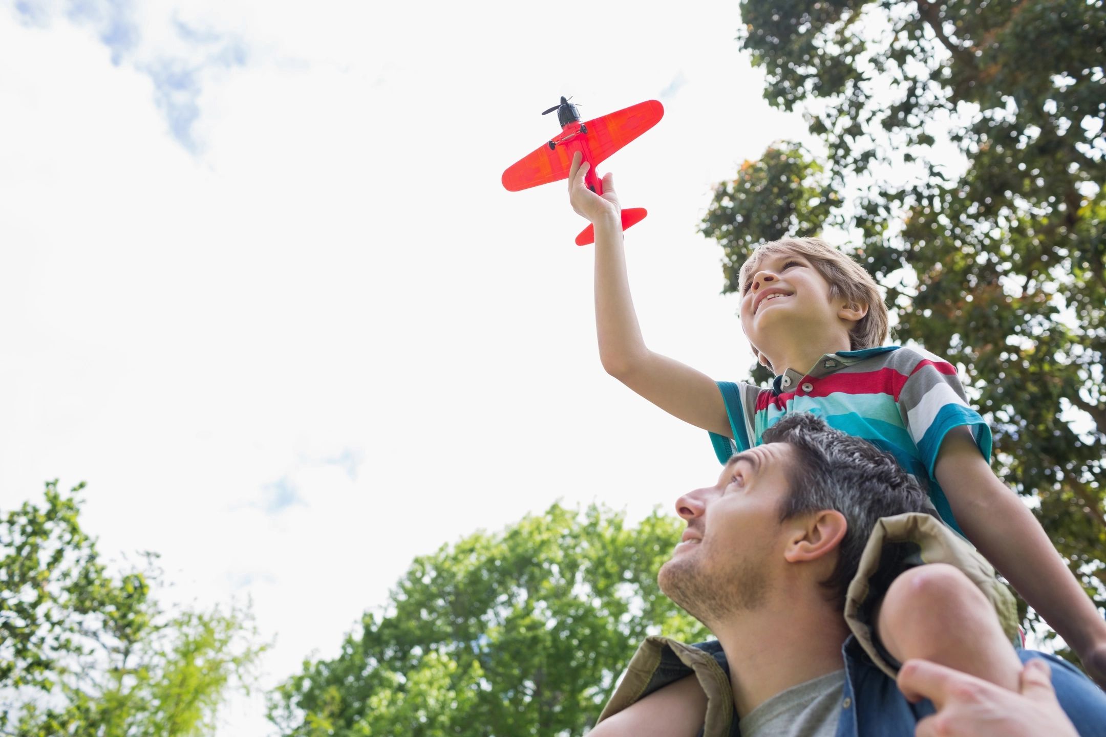 kid on shoulders flying toy airplane