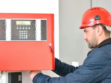 Man at Fire Alarm Panel - Fire & Life Safety Solutions by Associated Security Corporation