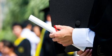 partial view of new graduate holding graduation cap and diploma